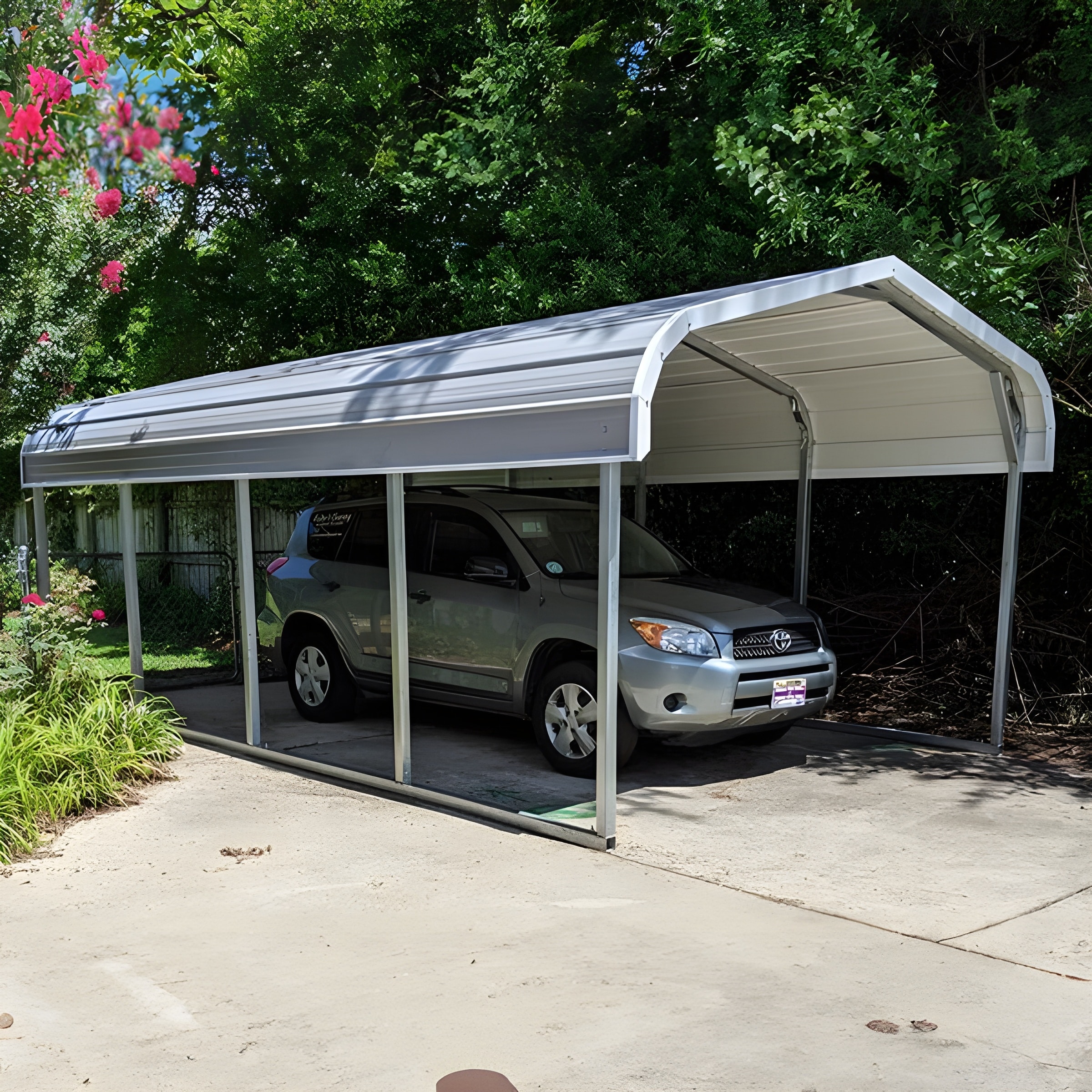 A sturdy metal carport made of steel, providing protection for vehicles. The carport is spacious and features a gable roof design. It is set against a background of a well-maintained driveway and a lush green garden.